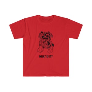 May include: Red t-shirt with a black and white illustration of a small dog. The text "WHAT IS IT?" is printed below the dog.
