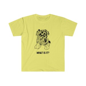 May include: A yellow t-shirt with a black and white illustration of a dog. The text "WHAT IS IT?" is printed below the dog.