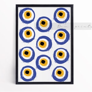 May include: Framed art print featuring a pattern of stylized blue and yellow evil eye symbols on a white background. The artwork is in a black frame and includes the text "Dam prints" in the upper right corner.