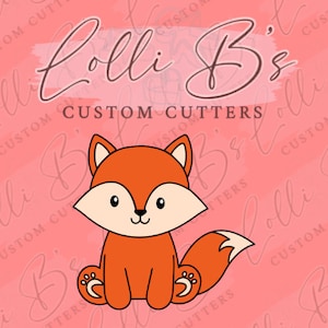 May include: A digital illustration of a cute orange fox sitting with its tail curled around its body. The fox has a white belly, black eyes, and a black nose. The background is a pink and white pattern with the text "Lolli B's Custom Cutters".