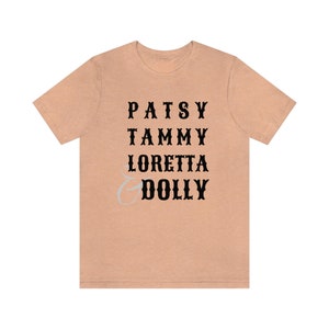 May include: A peach-colored t-shirt with black text that reads "Patsy Tammy Loretta & Dolly".