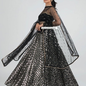 May include: A black and silver sequined lehenga with a sheer black dupatta. The lehenga has a chevron pattern and the dupatta has a delicate floral design.