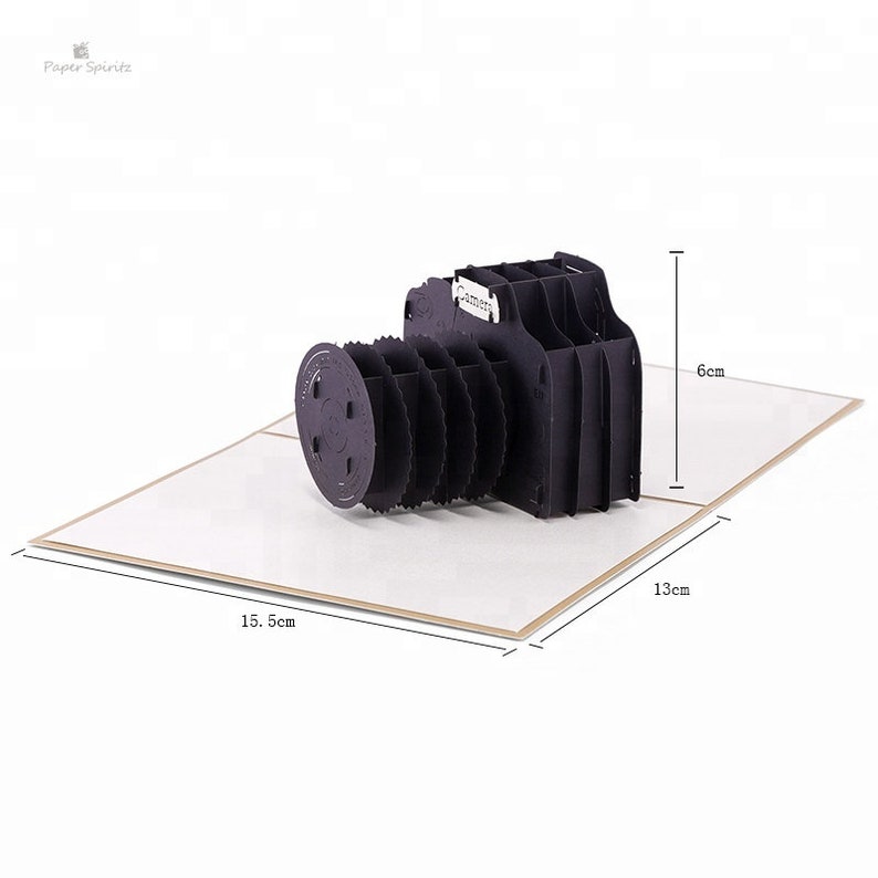 May include: A black paper pop-up card shaped like a camera. The card is 15.5 inches wide, 13 inches long, and 6 inches tall.