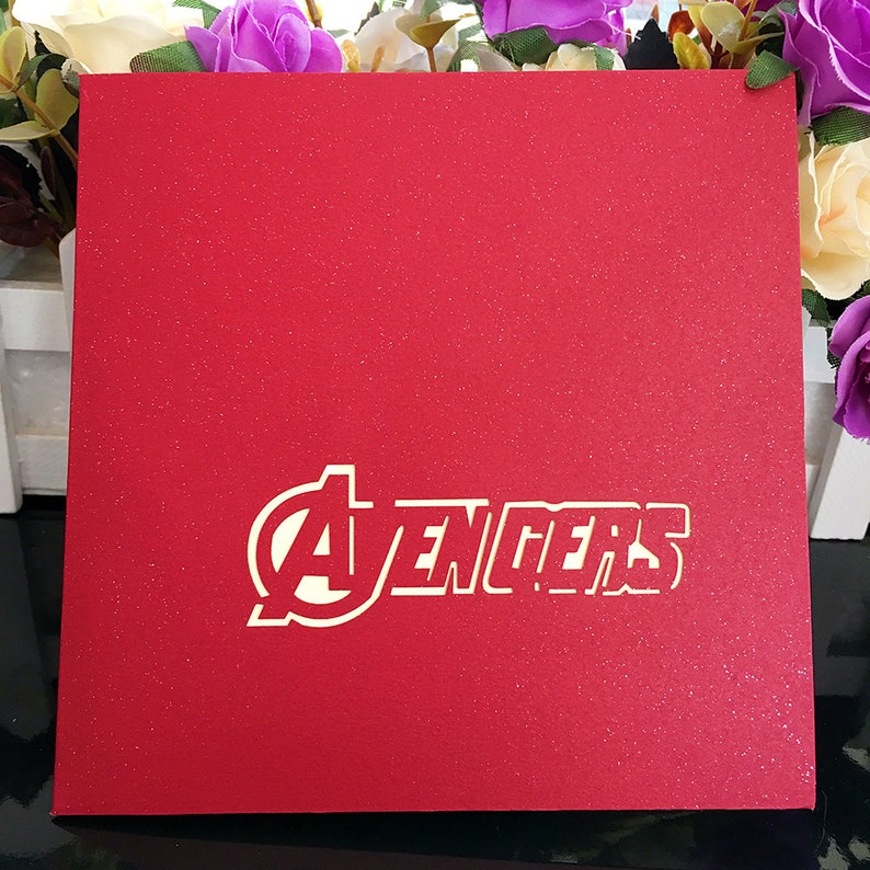 May include: Red card with a white "Avengers" logo. The logo is in a circle with a star inside.
