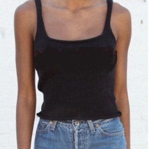May include: A black spaghetti strap tank top with a slightly cropped fit. The tank top is made of a soft, stretchy fabric.