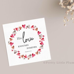 May include: A white card with a watercolor wreath of pink and gray hearts. The text inside the wreath reads "His love endures forever, Psalm 136:1".