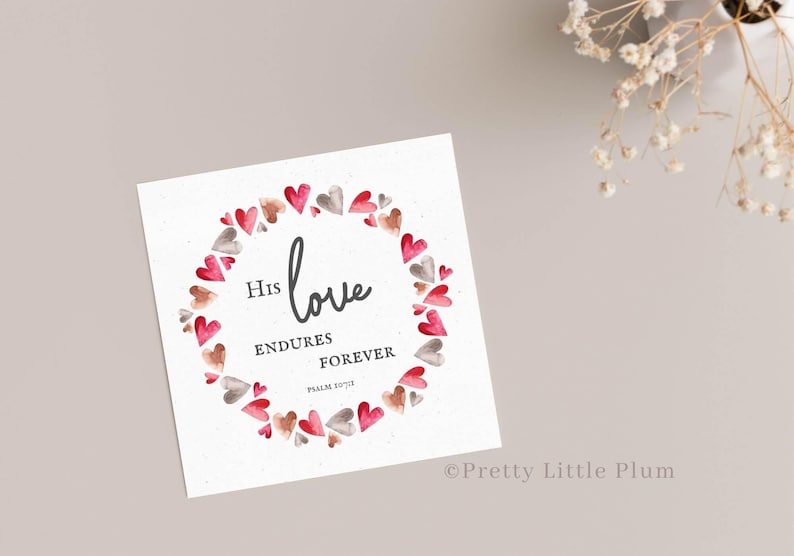 May include: A white card with a watercolor wreath of pink and gray hearts. The text inside the wreath reads "His love endures forever, Psalm 136:1".