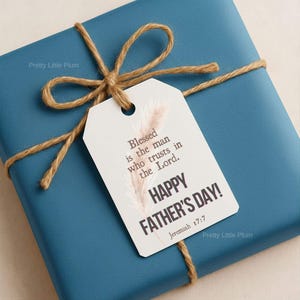 Könnte beinhalten: Eine tealfarbene Geschenkbox, die mit Bindfaden und einem Anhänger mit der Aufschrift "Happy Father's Day!" und einem Bibelzitat versehen ist. Der Anhänger hat auch einen dekorativen Zweig. Das Geschenk ist mit einer Bindfaden-Schleife gebunden.