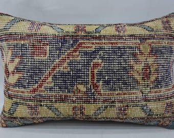 May include: A rectangular throw pillow with a colorful geometric pattern in shades of blue, red, and beige. The pillow is made of woven fabric and has a fringed edge.