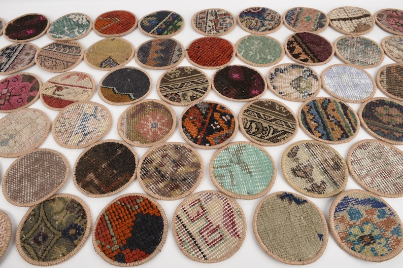 May include: A collection of oval-shaped coasters with intricate rug patterns. The coasters feature a variety of colors, including red, blue, green, and brown, with a beige border. These decorative coasters are ideal for protecting surfaces.