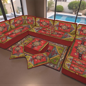 May include: A sectional sofa with a red base and patterned cushions and pillows. The cushions and pillows feature a design with red, green, yellow, and blue elements. A matching rug is also visible.