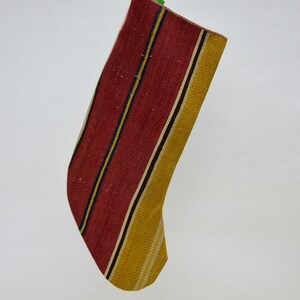 May include: A red and yellow striped Christmas stocking made of woven fabric.
