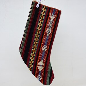Könnte beinhalten: Ein bunter, gestrickter Strumpf mit einem geometrischen Muster in Rot-, Schwarz-, Blau-, Grün- und Weißtönen.