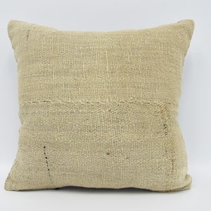May include: A square, off-white throw pillow with a woven texture. The pillow is made of natural fibres and has a rustic, handmade look.
