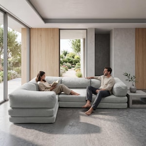 May include: A large, light gray sectional sofa with a textured fabric finish and low-profile, rounded armrests. The modular seating arrangement features deep cushions and a wide, L-shaped configuration, providing ample space for multiple people.