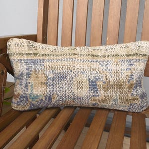 May include: A blue and beige patterned throw pillow with a woven texture sits on a wooden chair.