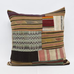 Pode incluir: Almofada quadrada de patchwork com uma variedade de padrões de tecido tecido. A almofada apresenta uma mistura de cores, incluindo castanho, bege, vermelho e verde. O design inclui listras, formas geométricas e elementos texturizados, criando uma estética rústica e artesanal.