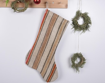 May include: A striped Christmas stocking with red, orange, and brown stripes on a beige background.