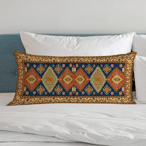 May include: A rectangular lumbar cushion featuring a vibrant, intricate pattern of repeating diamonds and geometric shapes in shades of deep blue, burnt orange, mustard yellow, and cream, finished with a decorative border along all four edges.