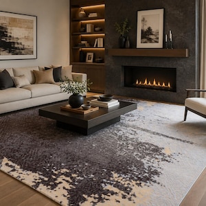 May include: A large rectangular area rug featuring an abstract pattern with deep charcoal grey, cream, and subtle gold tones. The design displays a distressed, textured appearance with dark concentrated areas transitioning into lighter, mottled sections.