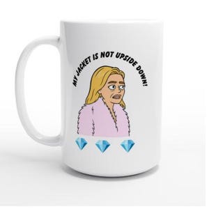 May include: White ceramic mug with a cartoon illustration of a woman wearing a pink fur coat. The text "MY JACKET IS NOT UPSIDE DOWN!" is printed above the woman's head. Three blue diamonds are below the woman.