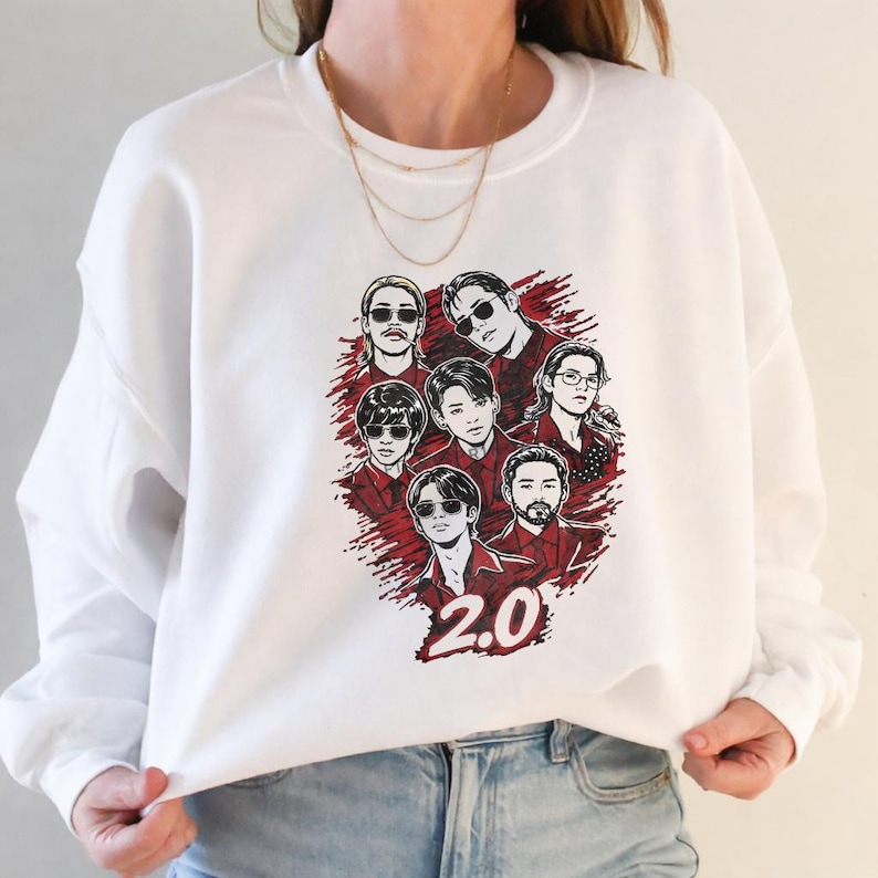 May include: White crewneck sweatshirt featuring a graphic of seven people with sunglasses and red accents. The number "2.0" is printed in red at the bottom. The sweatshirt is made of a soft material.
