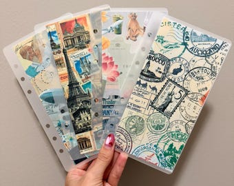 Könnte beinhalten: Eine Sammlung klarer Kunststoff-Ordner-Einsätze mit Reise-Themen-Designs. Jeder Einsatz zeigt verschiedene Bilder, darunter Briefmarken, Wahrzeichen und Illustrationen. Die Einsätze werden zusammengehalten und zeigen eine Vielzahl von Farben und Designs.