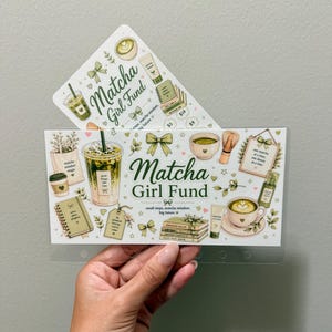 May include: A clear plastic cash envelope featuring the text Matcha Girl Fund and illustrations of matcha drinks, bows, books, and skincare products. The design includes a cup of iced matcha, a bowl with a whisk, and a framed sign with text.