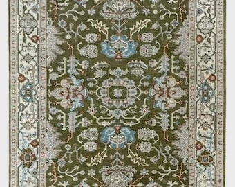 May include: An olive green area rug with an intricate floral pattern. The rug features a central medallion design with blue and cream accents, framed by a detailed border in cream, brown, and gray tones. The rug has a fringed edge.
