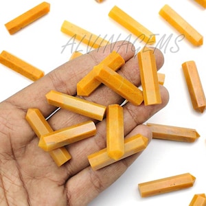 Op de afbeelding: Een verzameling van 20 gele citrienkristalpunten, ook wel bekend als citroenkwarts, gerangschikt op een wit oppervlak. De kristallen zijn glad en gepolijst, met een puntige punt en een platte basis. De kristallen zijn ongeveer 2,5 tot 5 cm lang.