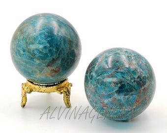 May include: Two blue-green gemstone spheres with swirling patterns. One sphere rests on a gold-colored, ornate stand. The spheres have a polished finish. The text "ALVINAGEMS" is visible on the bottom of the image.