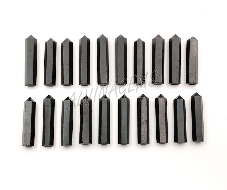 K&ouml;nnte beinhalten: Ein Set mit 18 schwarzen Obsidian-Kristallspitzen, jede etwa 5 cm lang. Die Spitzen sind in zwei Reihen zu je neun angeordnet, wobei die Spitzen nach oben zeigen.