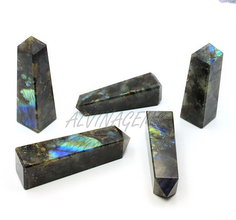 May include: Five labradorite obelisks with a dark gray base color and iridescent blue, green, and yellow flashes. The obelisks are rectangular with a pointed top. The word "ALVINAGENS" is visible in the image.