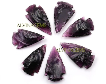 May include: Seven purple arrowhead shaped pieces of obsidian, arranged in a circle on a white background.  The text "ALVINAGEMS" appears twice in the image.