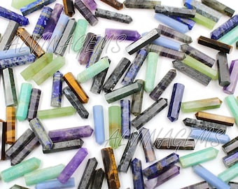May include: A collection of various colored gemstone points, including amethyst, lapis lazuli, tiger's eye, and green aventurine. The points are arranged on a white background.