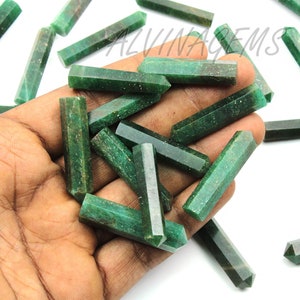 May include: A collection of green gemstone points, also known as wands, are displayed on a hand. The points are approximately 2 inches long and have a hexagonal shape.
