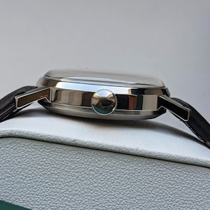 May include: A silver wristwatch with a black leather band. The watch has a round face and a silver case.