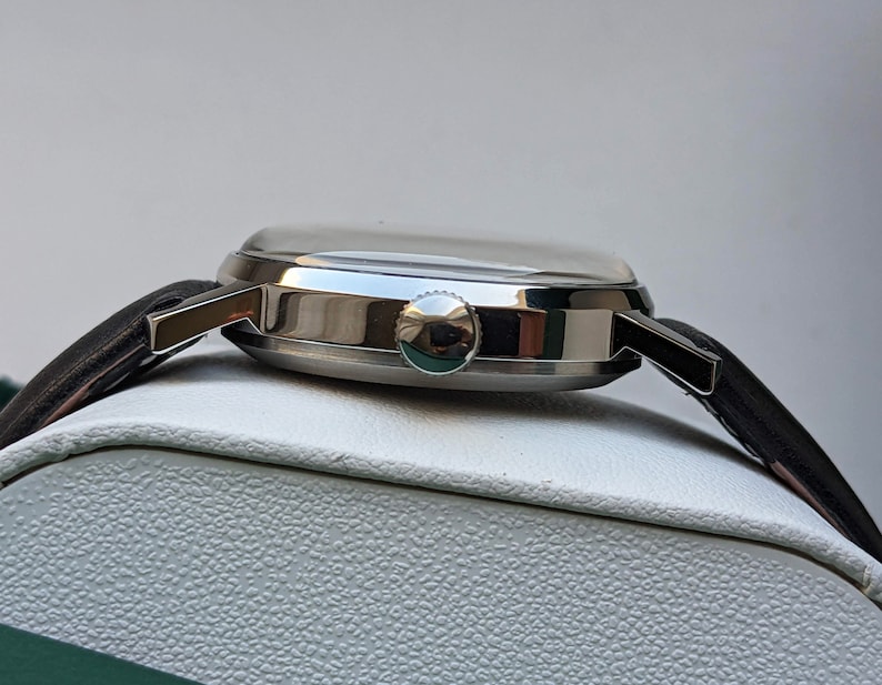 May include: A silver wristwatch with a black leather band. The watch has a round face and a silver case.