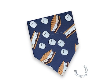 May include: A navy blue bandana with a pattern of brown and white s'mores. The bandana has a white border and the text "BRIGGS & RORK" is printed on the bottom right corner.