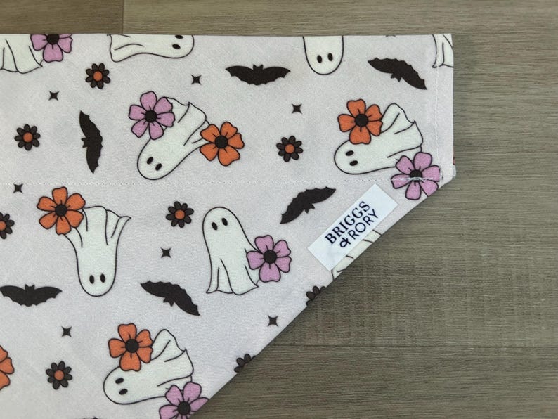 K&ouml;nnte beinhalten: Wei&szlig;er Baumwoll-Bandana mit einem sich wiederholenden Muster aus Geistern, Flederm&auml;usen und Blumen in Rosa, Orange und Schwarz. Der Bandana hat ein Etikett mit der Aufschrift "Briggs & Rory".