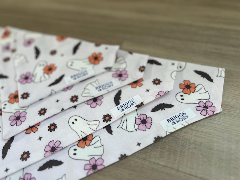 K&ouml;nnte beinhalten: Vier wei&szlig;e Stoff-Hundehalst&uuml;cher mit einem Geister- und Blumenmuster. Die Halst&uuml;cher haben ein schwarz-wei&szlig;es Etikett mit der Aufschrift "Briggs + Rory".