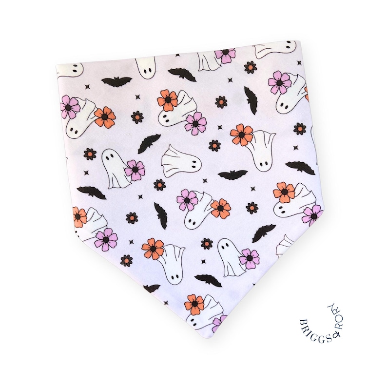 K&ouml;nnte beinhalten: Wei&szlig;es Bandana mit einem sich wiederholenden Muster aus Geistern, Flederm&auml;usen und Blumen in Rosa, Orange und Wei&szlig;. Das Bandana ist dreieckig und hat einen ausgefransten Rand.