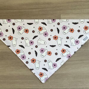 K&ouml;nnte beinhalten: Wei&szlig;er Baumwoll-Bandana mit einem sich wiederholenden Muster aus Geistern und Blumen in Rosa-, Orange- und Wei&szlig;t&ouml;nen. Der Bandana hat ein schwarz-wei&szlig;es Etikett mit der Aufschrift "Briggs & Rory".