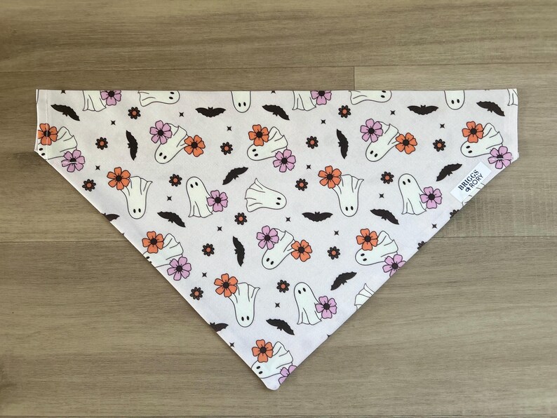 K&ouml;nnte beinhalten: Wei&szlig;er Baumwoll-Bandana mit einem sich wiederholenden Muster aus Geistern und Blumen in Rosa-, Orange- und Wei&szlig;t&ouml;nen. Der Bandana hat ein schwarz-wei&szlig;es Etikett mit der Aufschrift "Briggs & Rory".