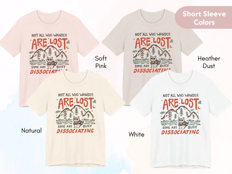May include: Four short-sleeved t-shirts with a graphic print of a cat in a forest with the text "Not all who wander are lost. Some are busy dissociating."