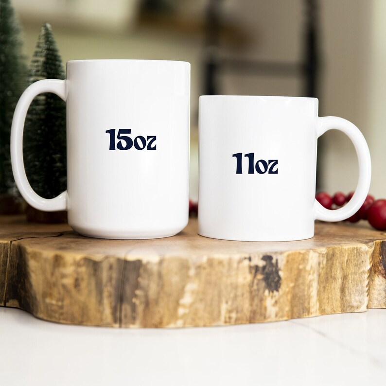 May include: Two white ceramic mugs with black text. The larger mug is 15oz and the smaller mug is 11oz.
