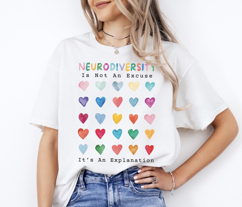 May include: White t-shirt with the text "Neurodiversity is not an excuse, it's an explanation." The text is in rainbow colors and is surrounded by a grid of 36 watercolor hearts in various colors.