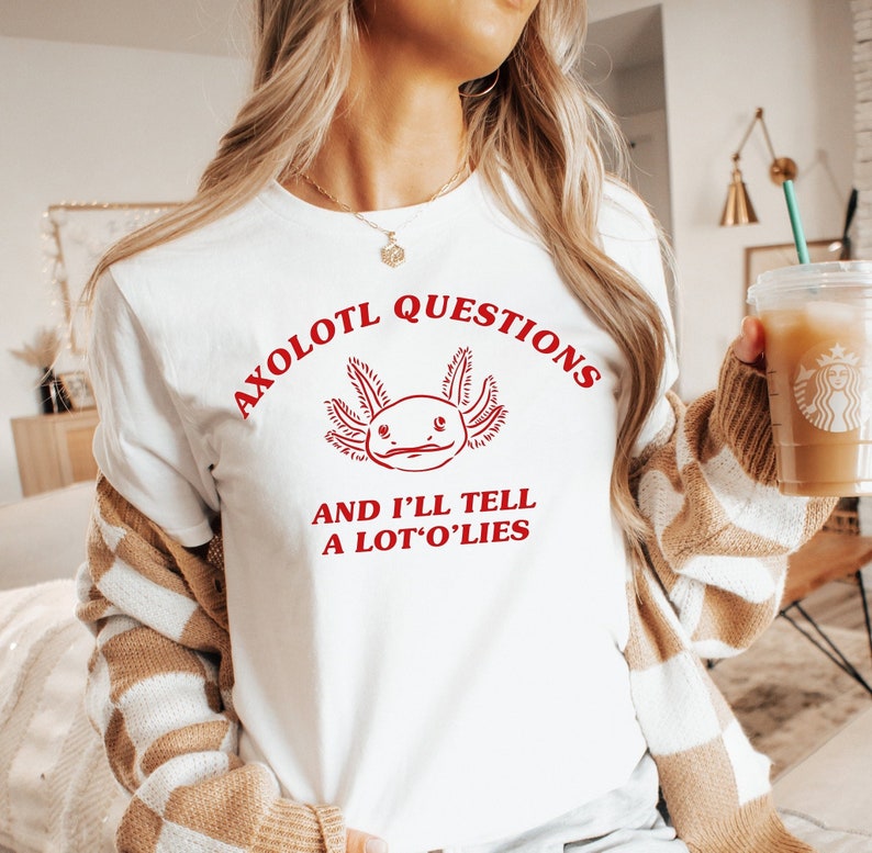 May include: White t-shirt with a red axolotl graphic and the text "Axolotl Questions and I'll Tell A Lot'O'Lies".