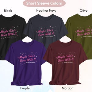 Puede incluir: Cinco camisetas de manga corta en diferentes colores con el texto "Maybe She's Born With It" impreso en la parte delantera. Los colores son negro, azul marino jaspeado, oliva, morado y granate.