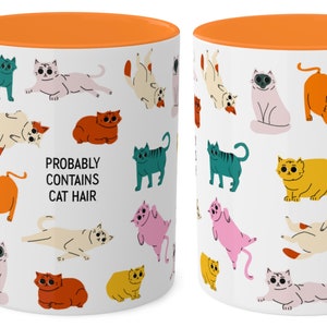 May include: White ceramic mug with an orange rim. The mug features a repeating pattern of colourful cartoon cats in various poses. The text "Probably Contains Cat Hair" is printed in black on the mug.